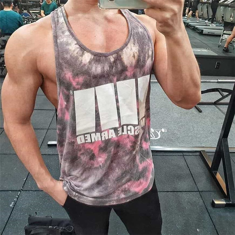 Person wearing a tie-dye tank top with visible branding in a gym setting