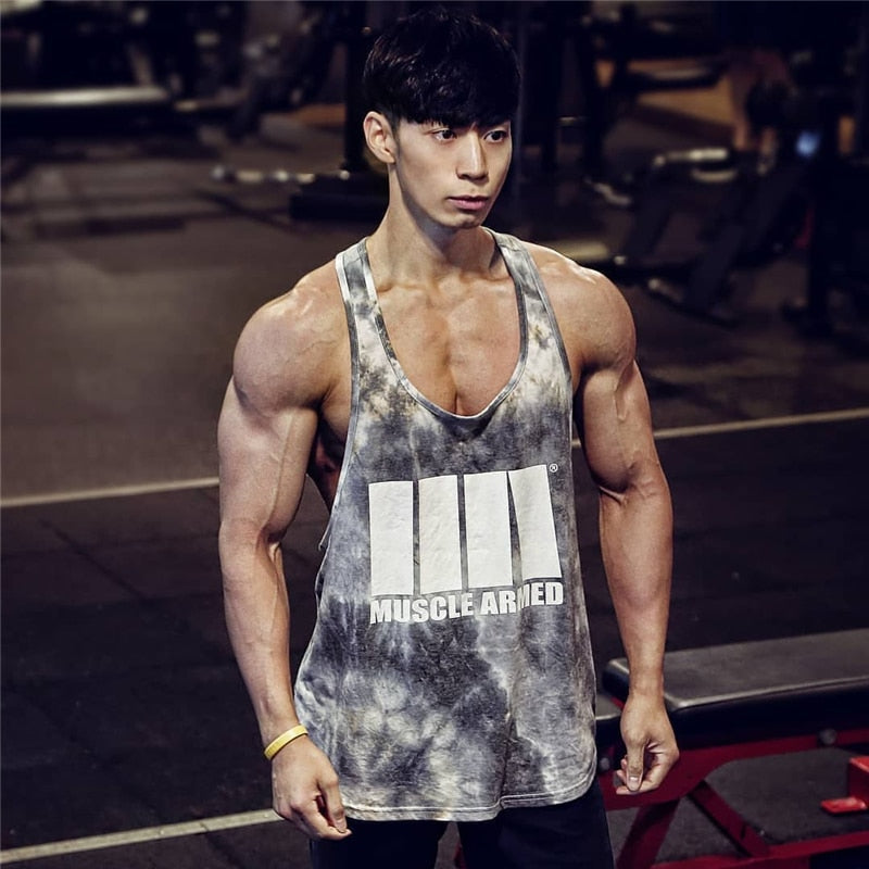 Muscular man wearing a 'Muscle Armed' tank top in a gym setting