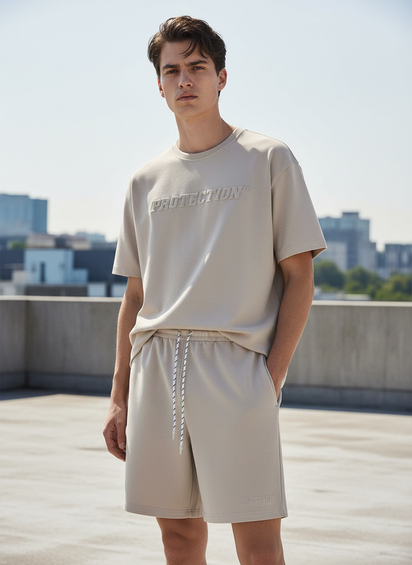 Man wearing a beige t-shirt and shorts on a rooftop with cityscape background