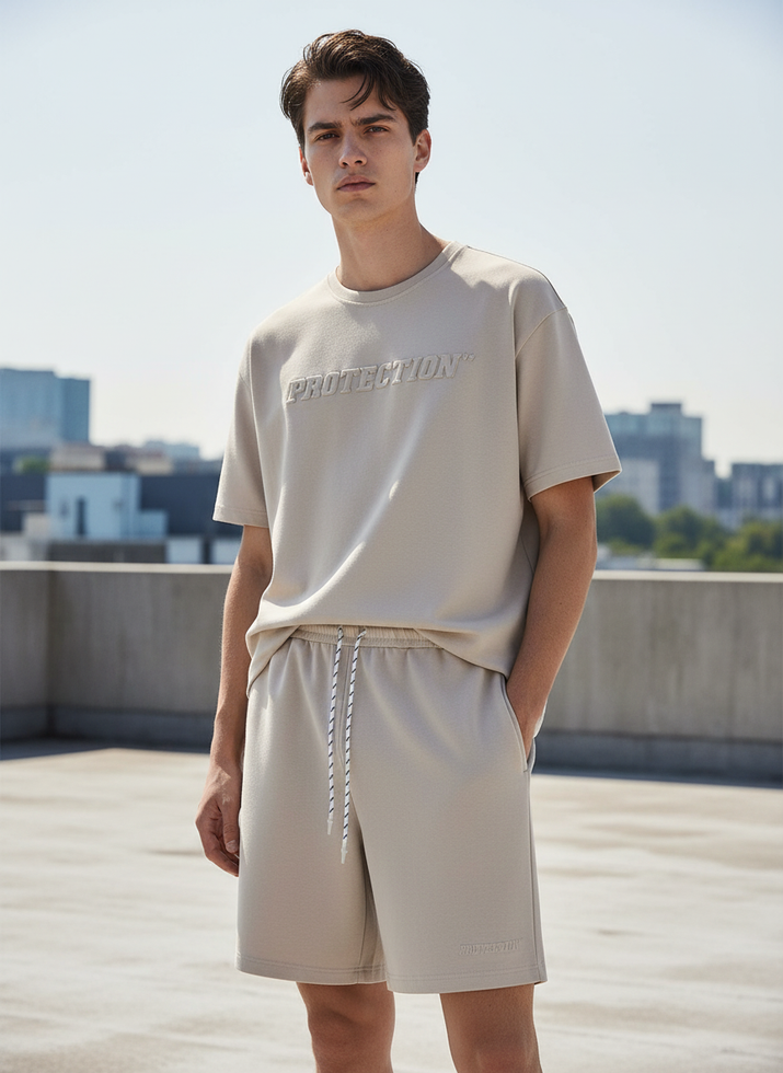 Man wearing a beige t-shirt and shorts on a rooftop with cityscape background